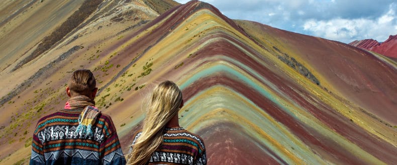 pareja de mochileros con sueters de alpaca en la montaña de 7 colores, Peru