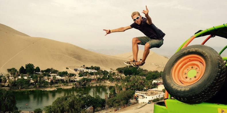 persona saltando en con desierto de huacachina al fondo - feriados en peru