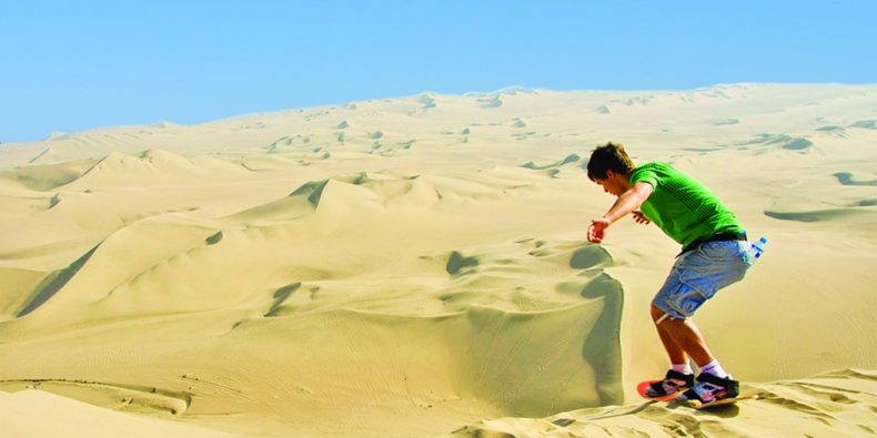 joven haciendo sandboarding en huacachina - feriados en peru